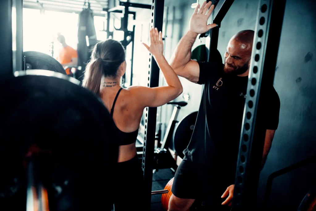 BTX client standing behind the dumbbell rack in the studio